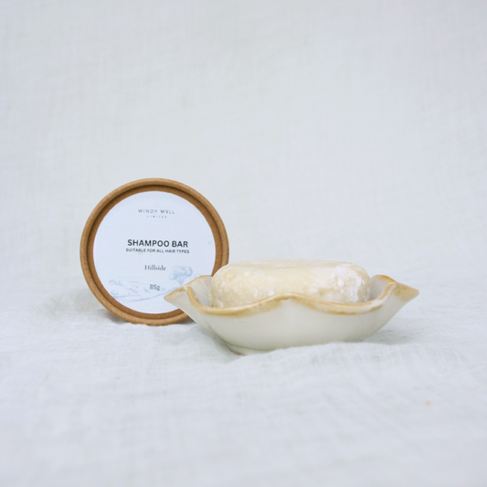 Shampoo bar with wooden lid and white container on a light gray background